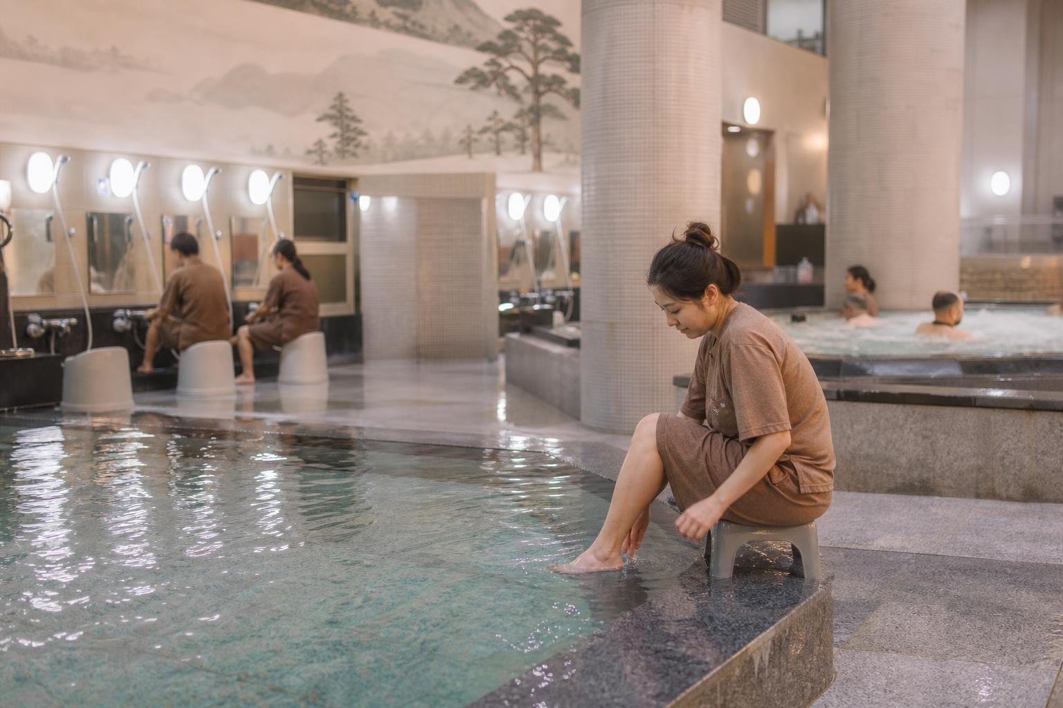 Guests wearing matching shorts and shirts resting on a heated floor in a shared jjimjilbang lounge